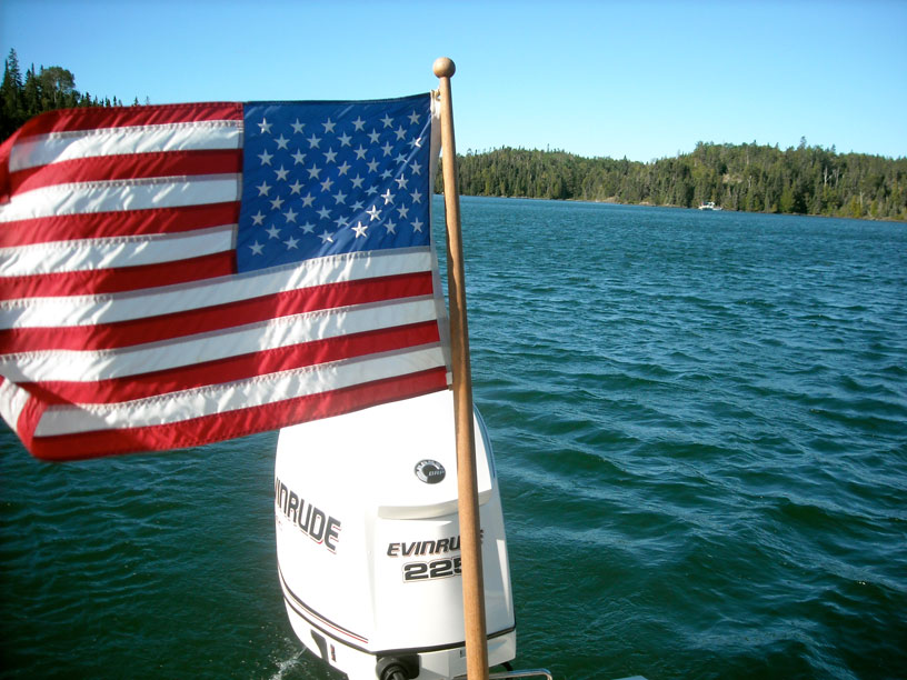 Photo: Morning wind blows the stern ensign out straight in Chippewa Harbor, Isle Royale, Lake Superior.